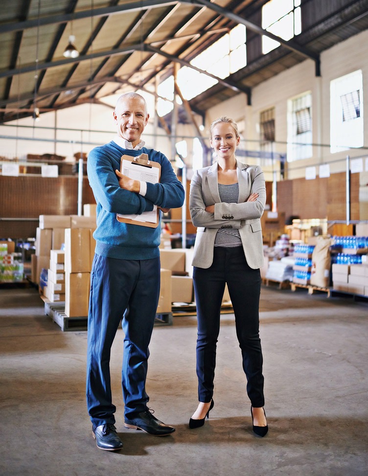 A man and a woman standing in front of a manufacturing company."